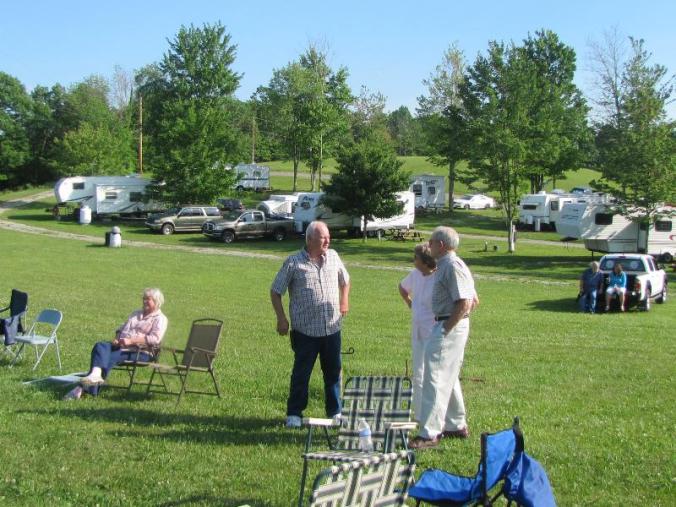Owner Steve Garten, center, chattng wth guests: a portion of the beautiful RV sites are in the background. 