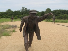 Statue of Wilbur running alongside the plane piloted by Orville